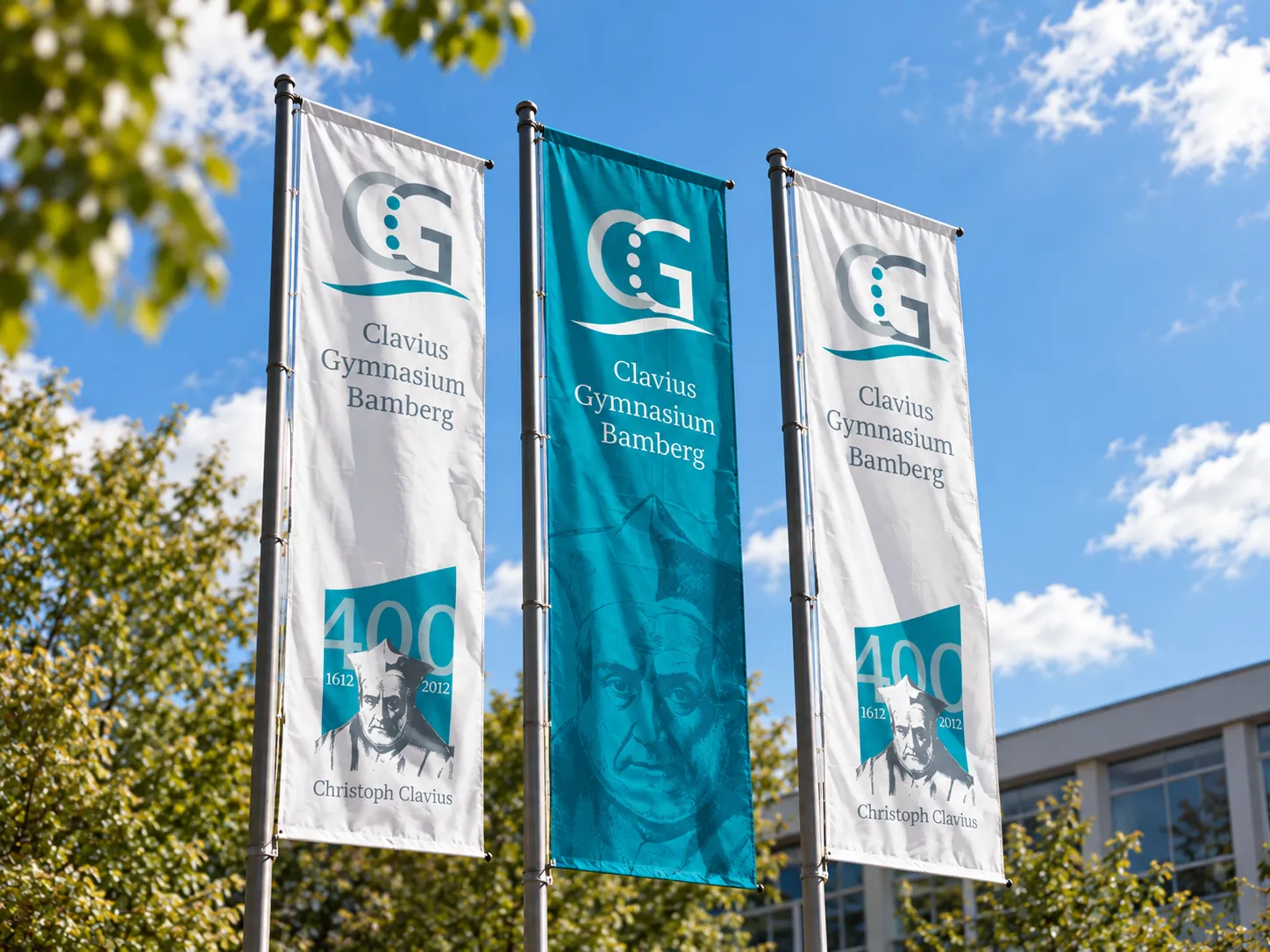 Drei Fahnen vor dem Schulgebäude, eine mit dem Porträt von Christophorus Clavius